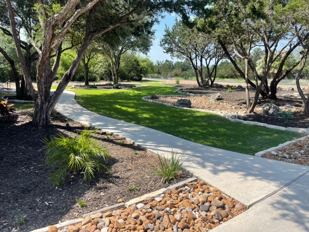 Canopy Land Solutions - Professional landscaping with curved pathways, fresh sod, mulch beds, and decorative rock in San Antonio